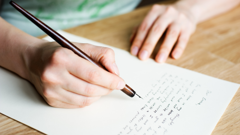 Girl writing a letter on wooden table