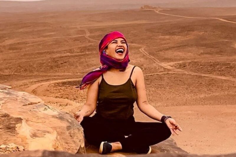 Girl sitting on a desert ground with stone beside her