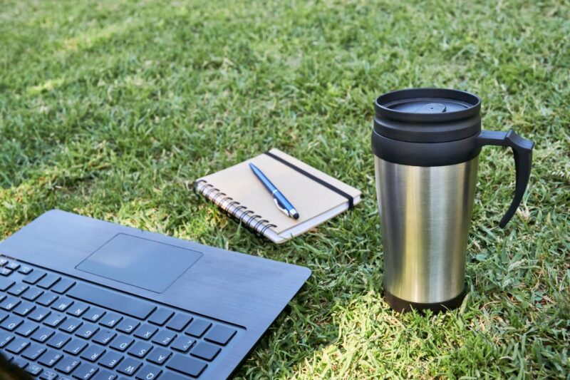 A travel mug with a laptop and notebook