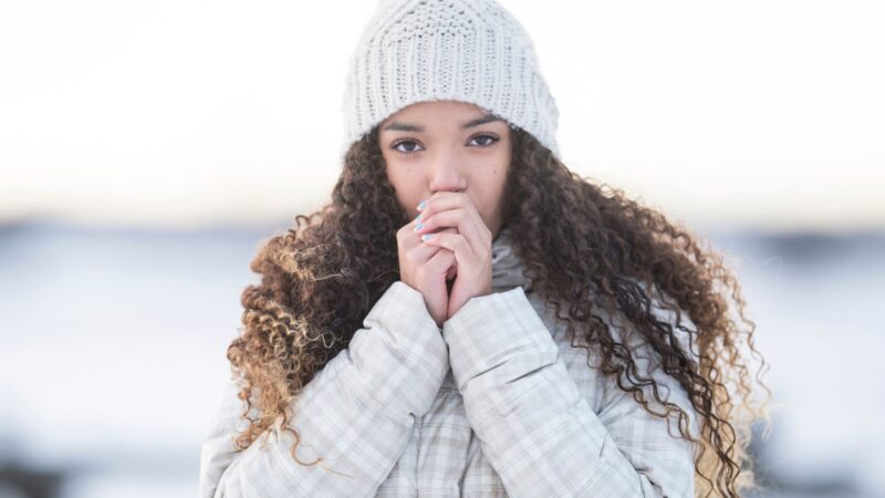 Girl blowing air into fists to keep warm