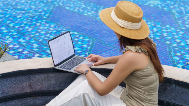 A girl working on her laptop by the pool