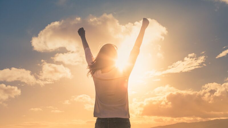 Girl standing in a field with arms up