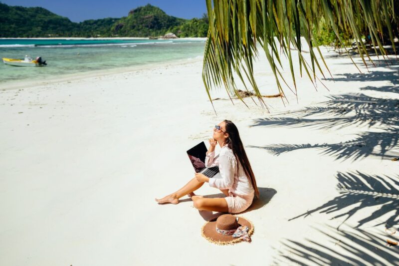 lady sitting at the beautiful beach with laptop