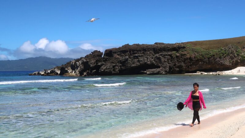 Woman walking along a clear beach in Batanes