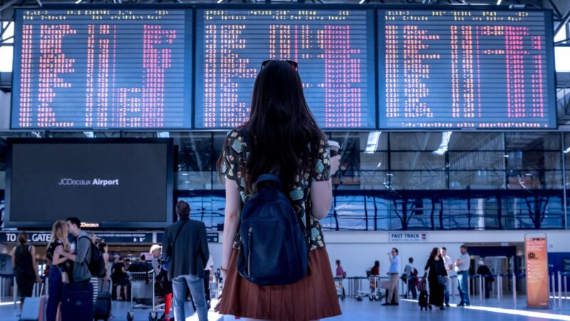 Girl in front of digital board for flight announcements