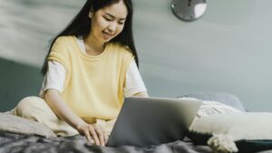 Woman at home using her laptop on bed