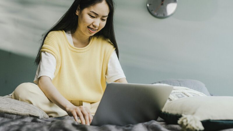 Woman at home using her laptop on bed