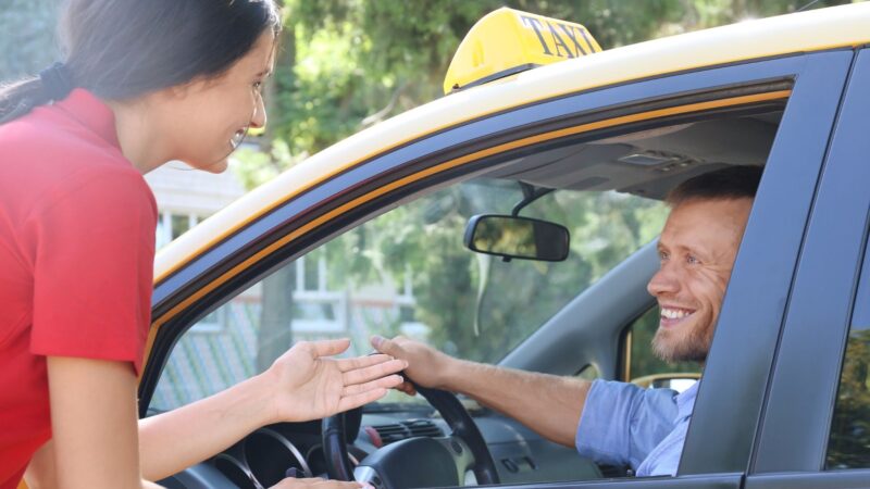 A woman talking to the driver of a taxi