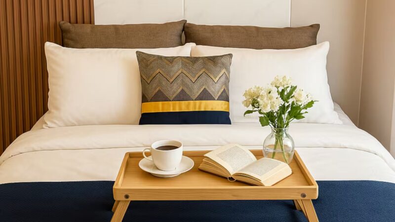 A big bed with white sheets and a mini table on it