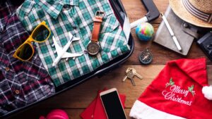 Luggage bag next to travel items and a Christmas hat