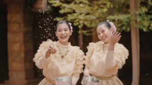 Two Thai women in traditional clothes splashing water