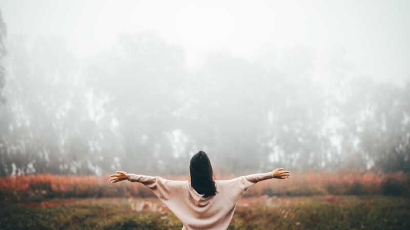 Girl opening her arms while standing on a field