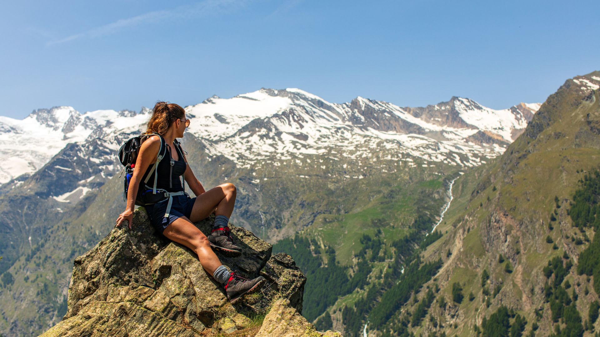 A girl sitting on a stone on a mountain